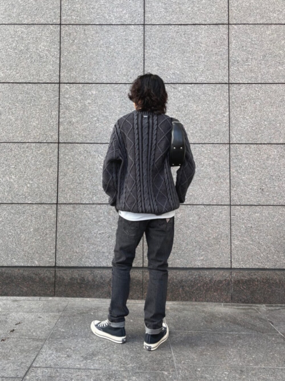 グレー系のデニムパンツ、ブラック系のショルダーバッグ、ブラック系のニット/セーターを着用したメンズの冬コーディネートの2枚目の写真