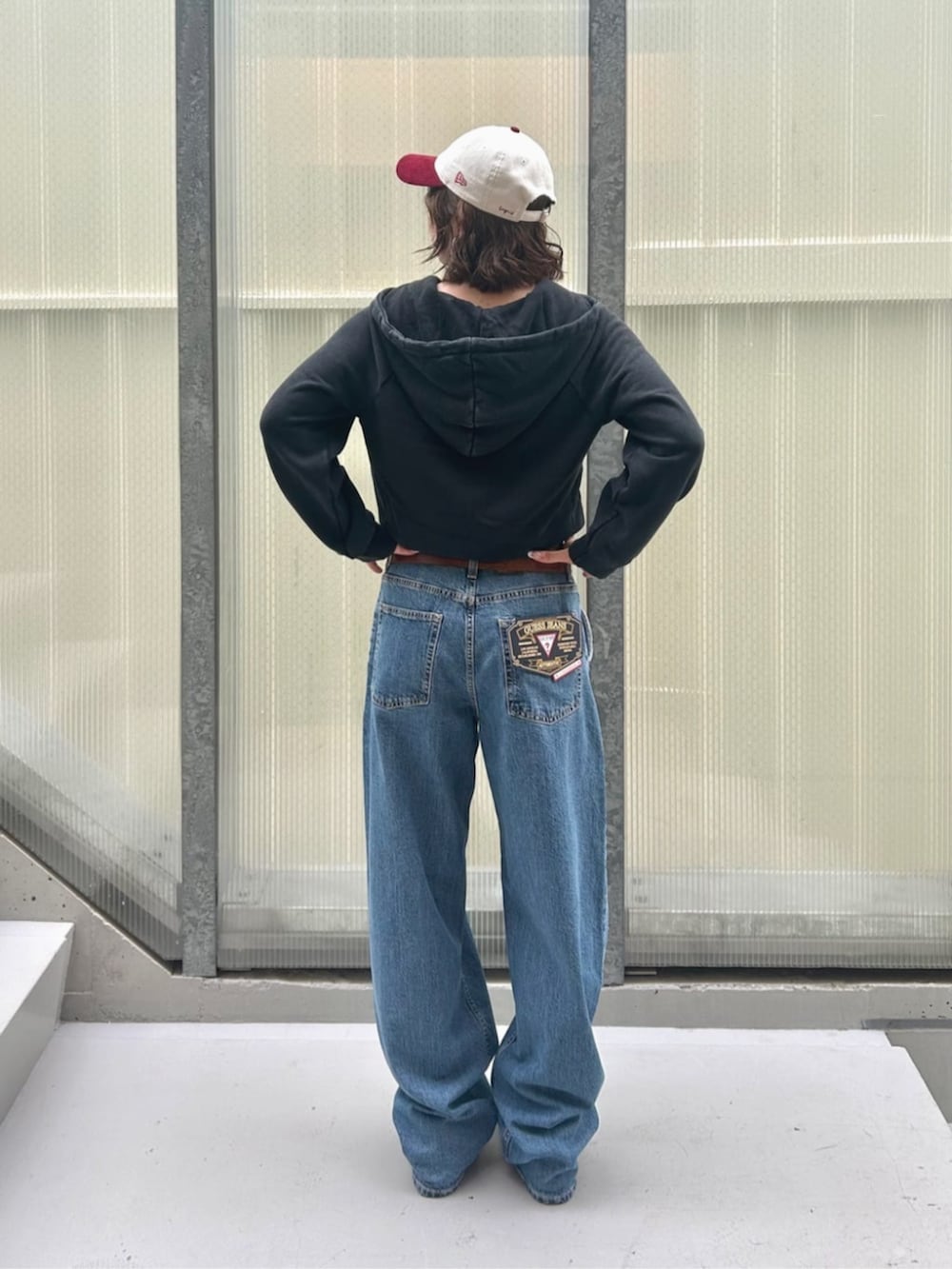 ブルー系のデニムパンツ、ブラック系のパーカー、ブラック系のボクサーパンツを着用したレディースの秋コーディネートの2枚目の写真