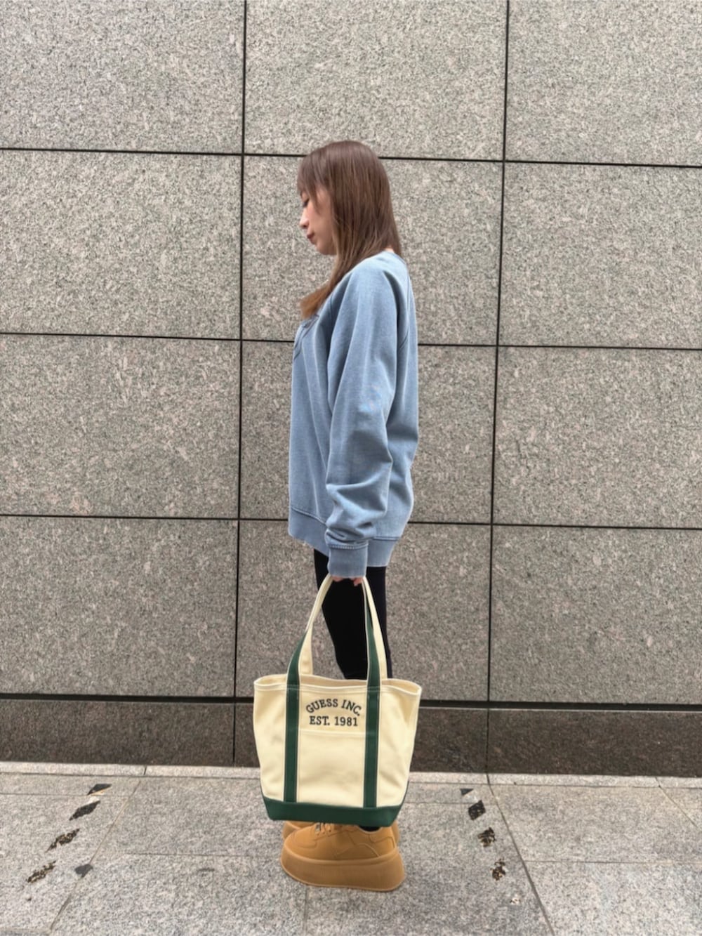 ブルー系のデニムパンツ、グリーン系のトートバッグ、ブルー系のスウェットを着用したレディースの秋コーディネートの3枚目の写真