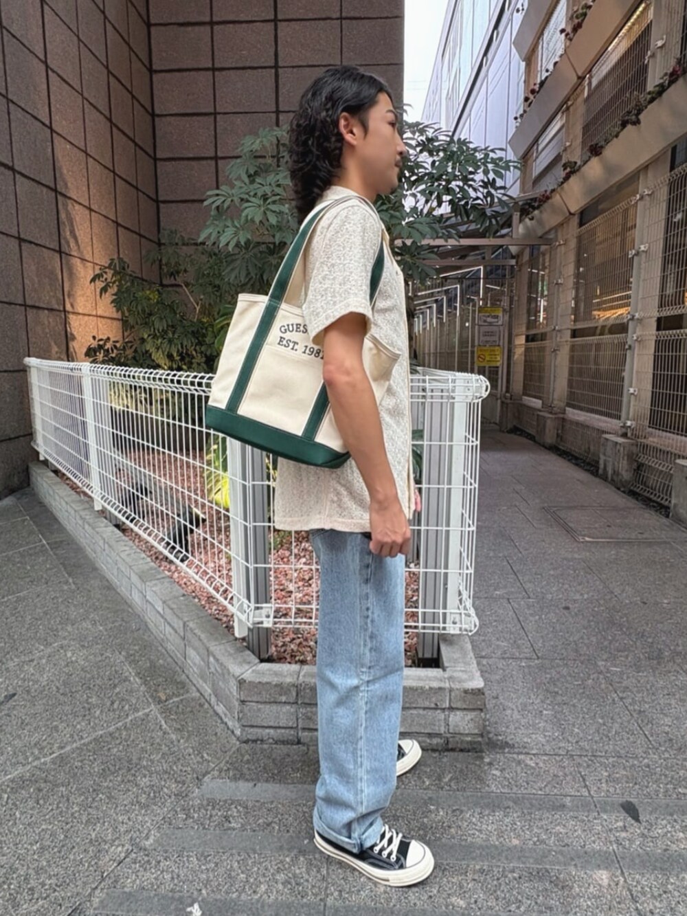 ブルー系のデニムパンツ、ホワイト系のシャツ/ブラウス、グリーン系のトートバッグを着用したメンズの夏コーディネートの3枚目の写真