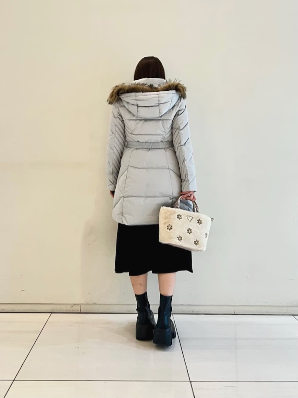 グレー系のダウンジャケット/コート、ブラック系のワンピース、ホワイト系のショルダーバッグを着用したレディースの冬コーディネートの2枚目の写真