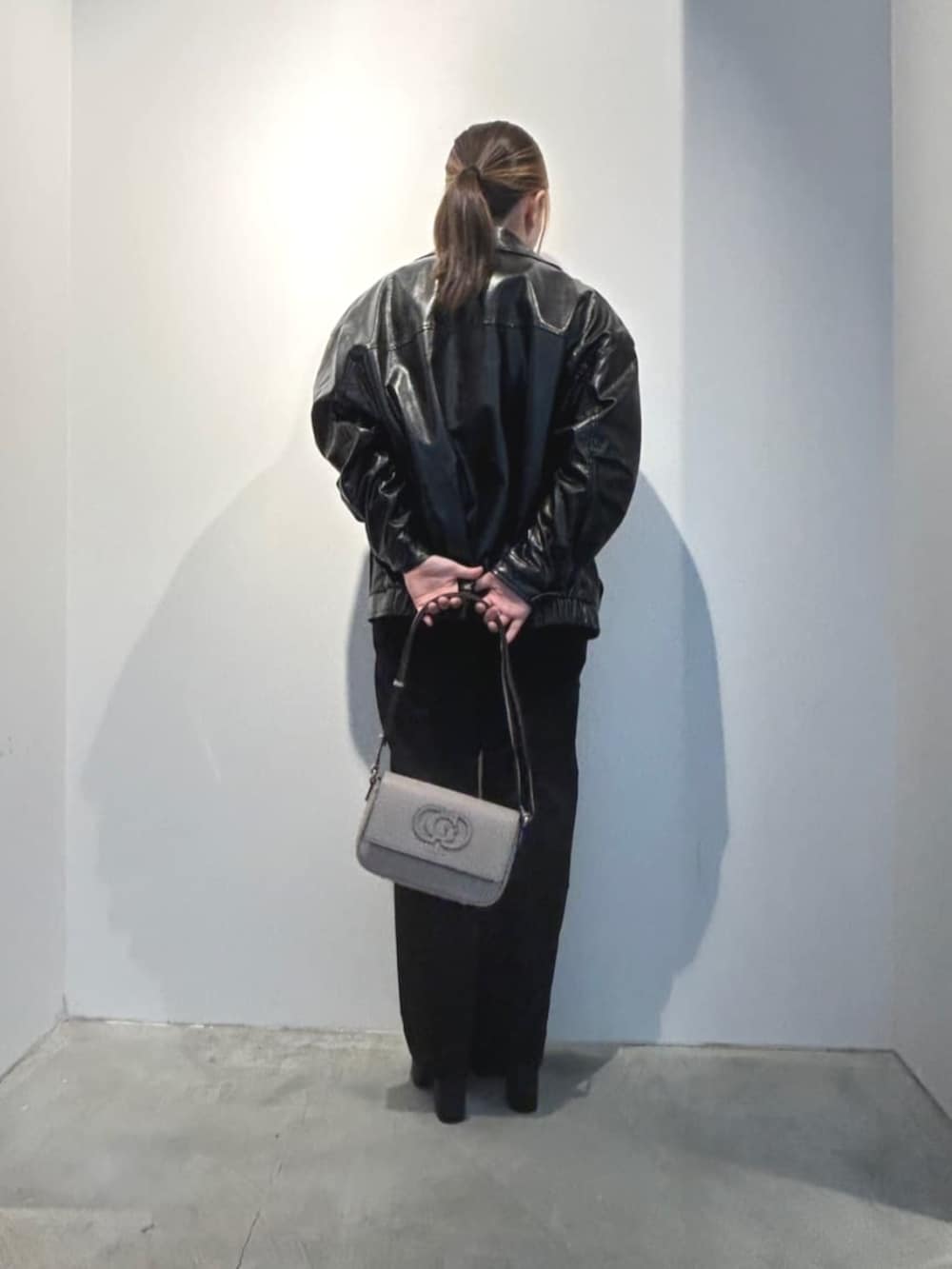 ブラック系のデニムパンツ、ベージュ系のショルダーバッグ、ブラック系のカバーオールを着用したレディースの春コーディネートの2枚目の写真