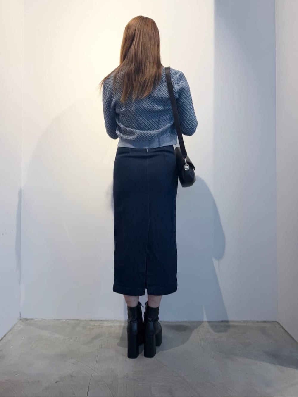 ブラック系のショルダーバッグ、ブルー系のワンピース、グレー系のニット/セーターを着用したレディースの冬コーディネートの2枚目の写真