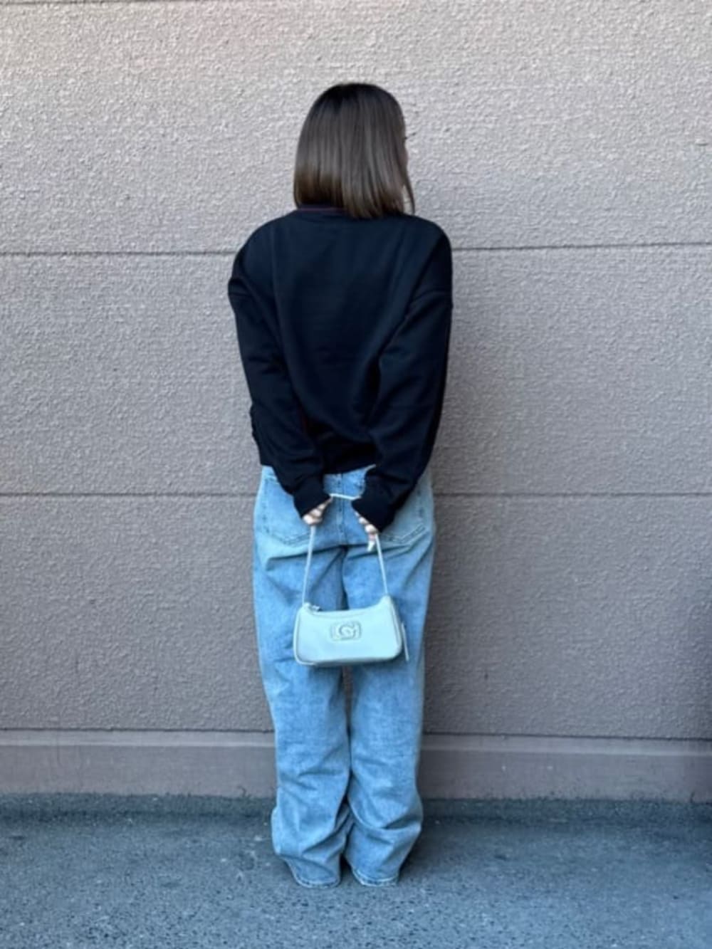 ブラック系のスウェット、ブルー系のデニムパンツを着用したレディースの春コーディネートの3枚目の写真