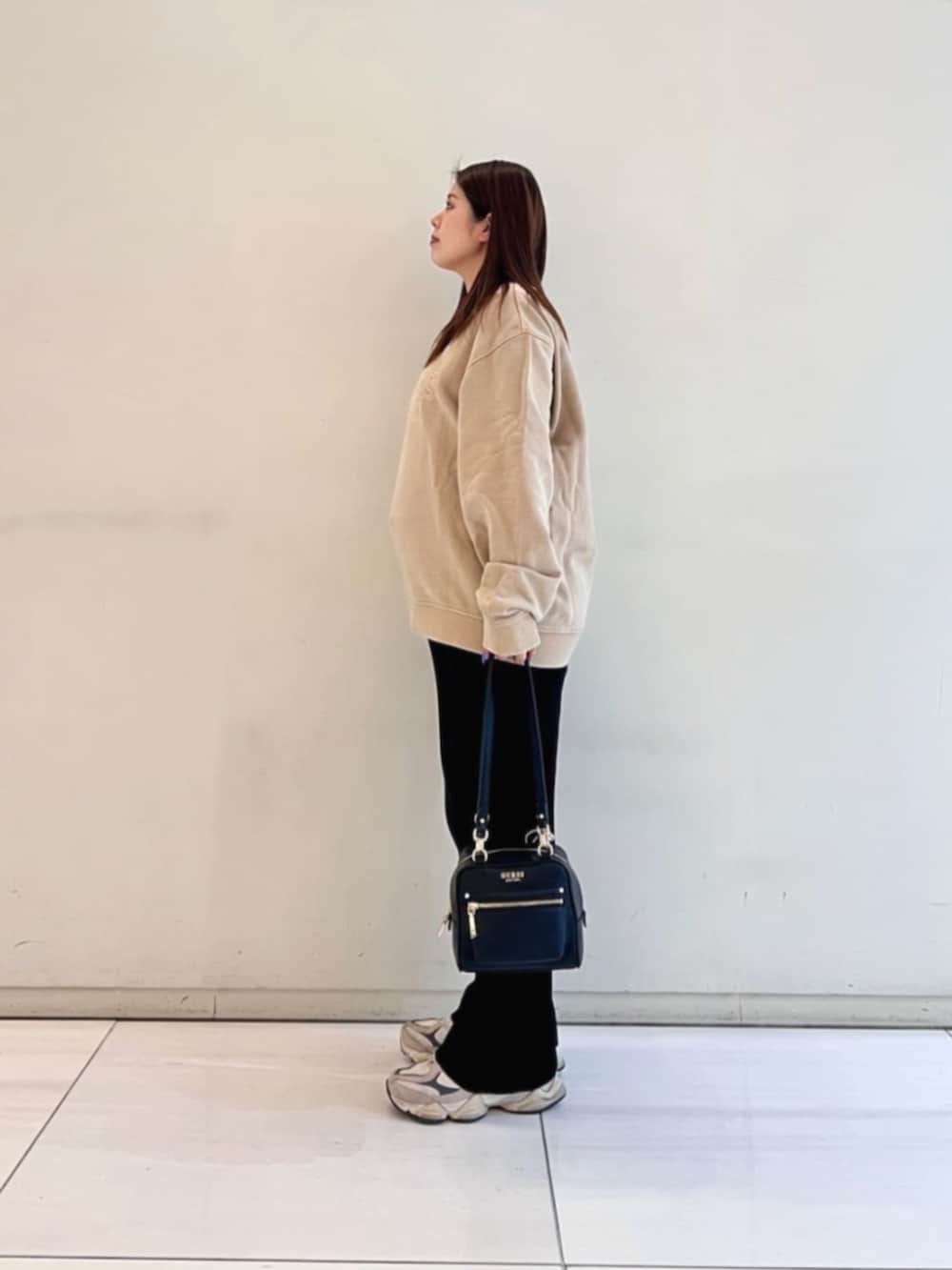 ブラック系のショルダーバッグ、ベージュ系のスウェットを着用したレディースの冬コーディネートの3枚目の写真