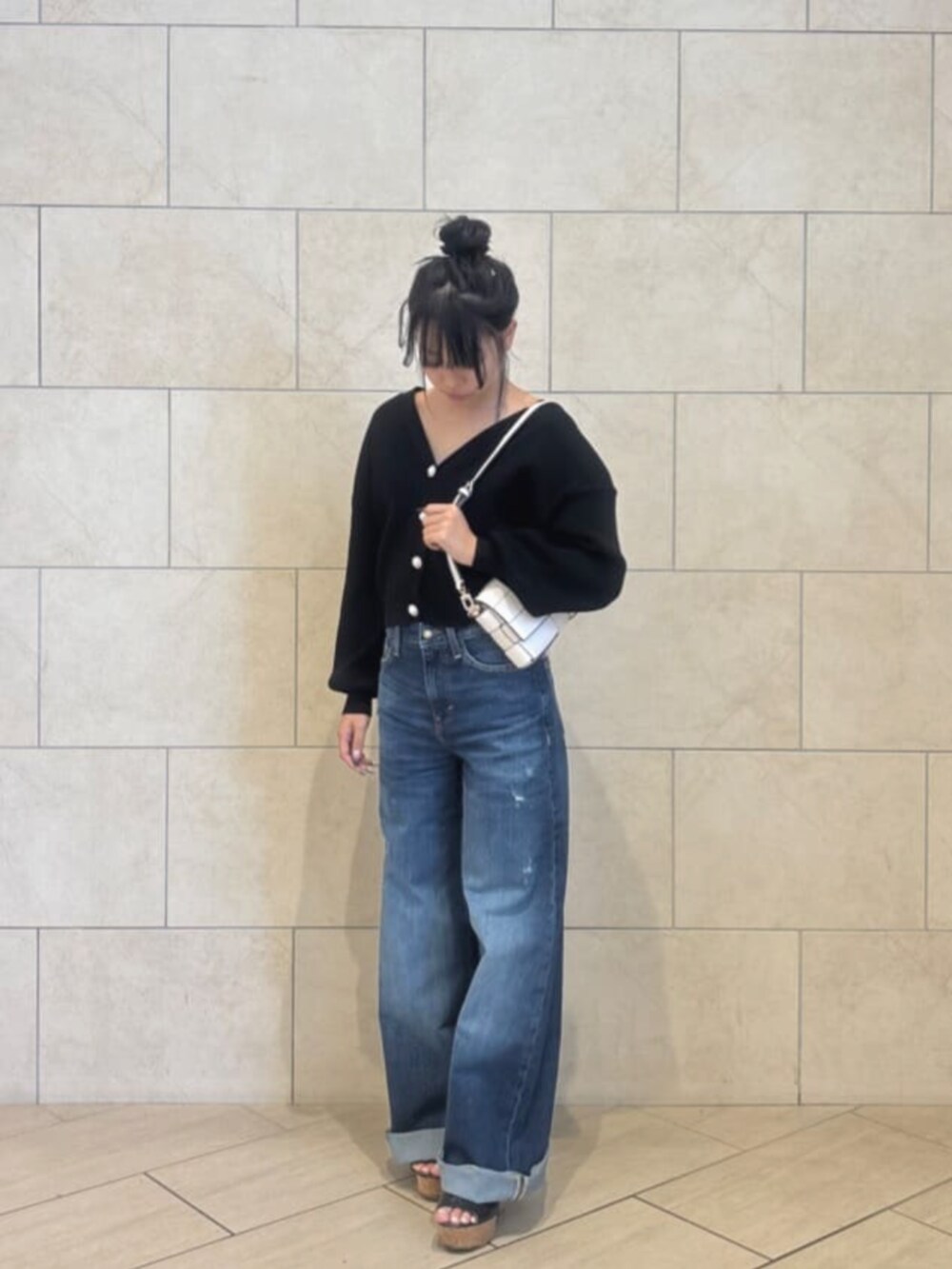 ブルー系のデニムパンツ、ホワイト系のショルダーバッグ、ブラック系のカーディガン/ボレロを着用したレディースの秋コーディネートの4枚目の写真