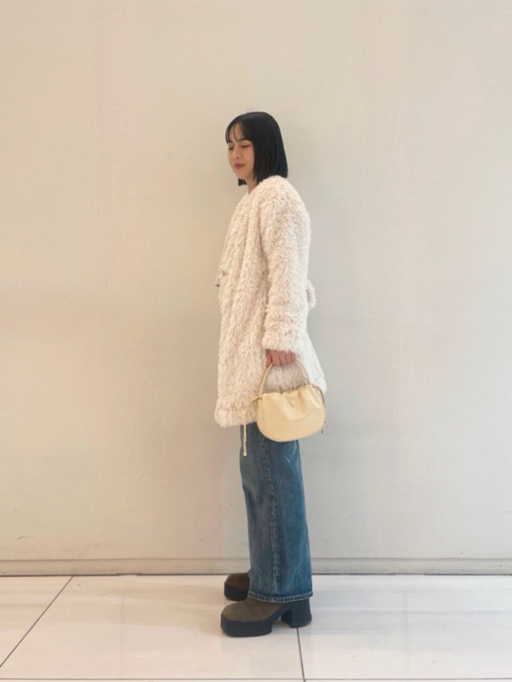 ブルー系のデニムパンツ、ホワイト系のカーディガン/ボレロ、ホワイト系のTシャツ/カットソーを着用したレディースの冬コーディネートの3枚目の写真