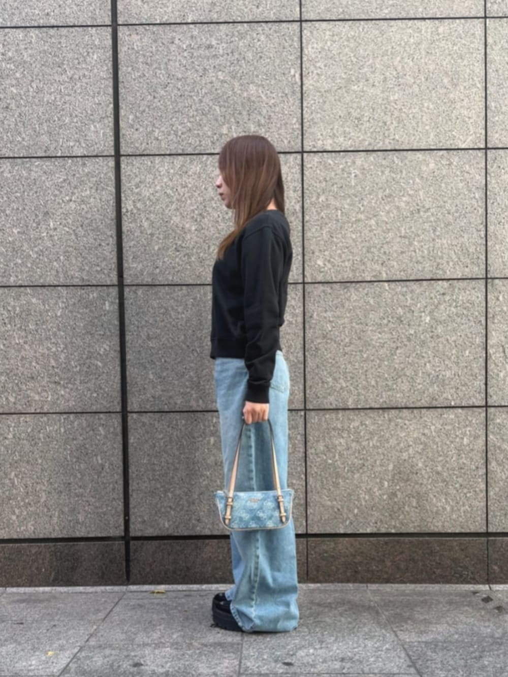 ブルー系のショルダーバッグ、ブラック系のスウェット、ブルー系のデニムパンツを着用したレディースの冬コーディネートの3枚目の写真