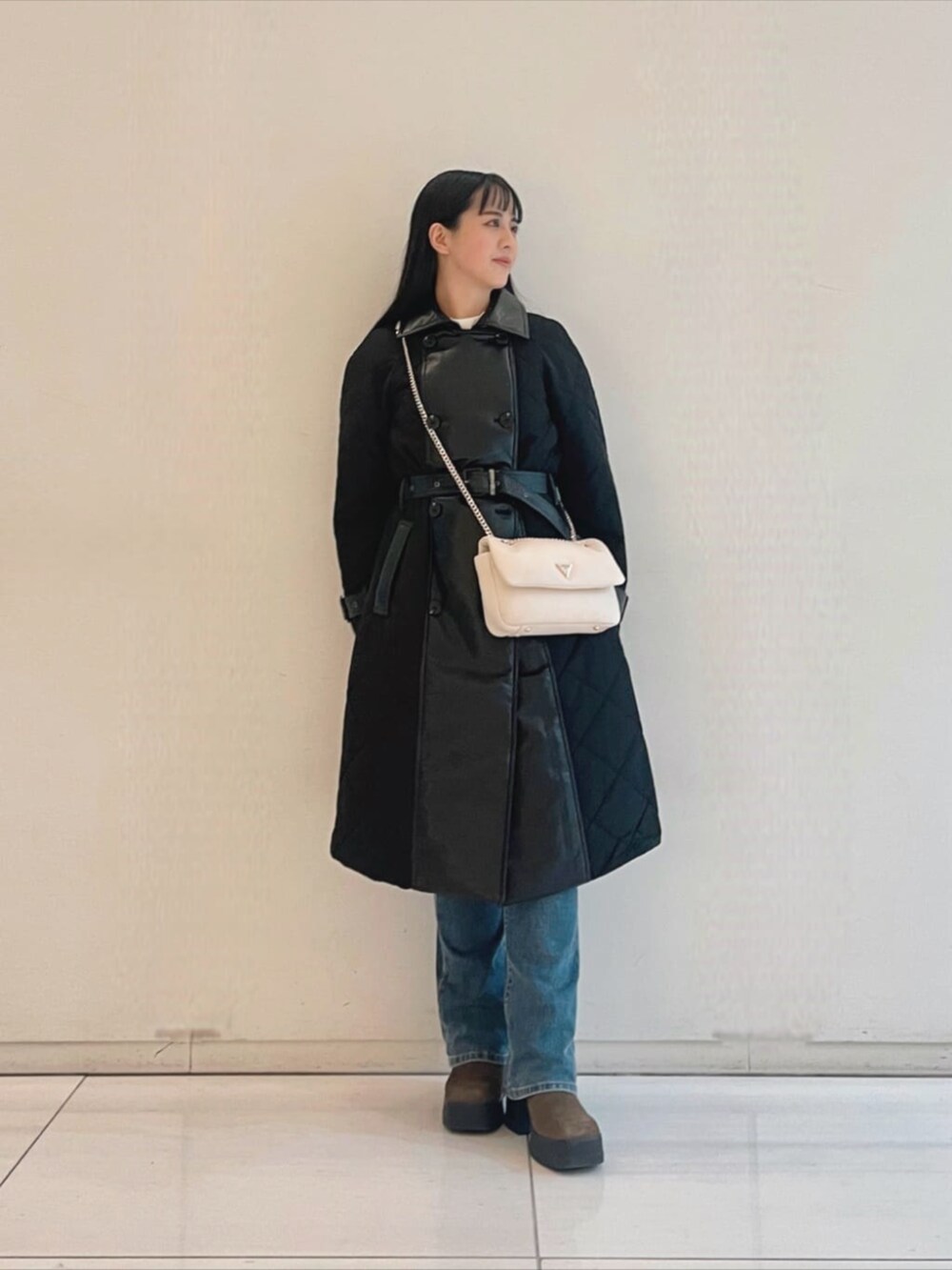 ブルー系のデニムパンツ、ホワイト系のニット/セーター、ホワイト系のショルダーバッグを着用したレディースの秋コーディネートの4枚目の写真