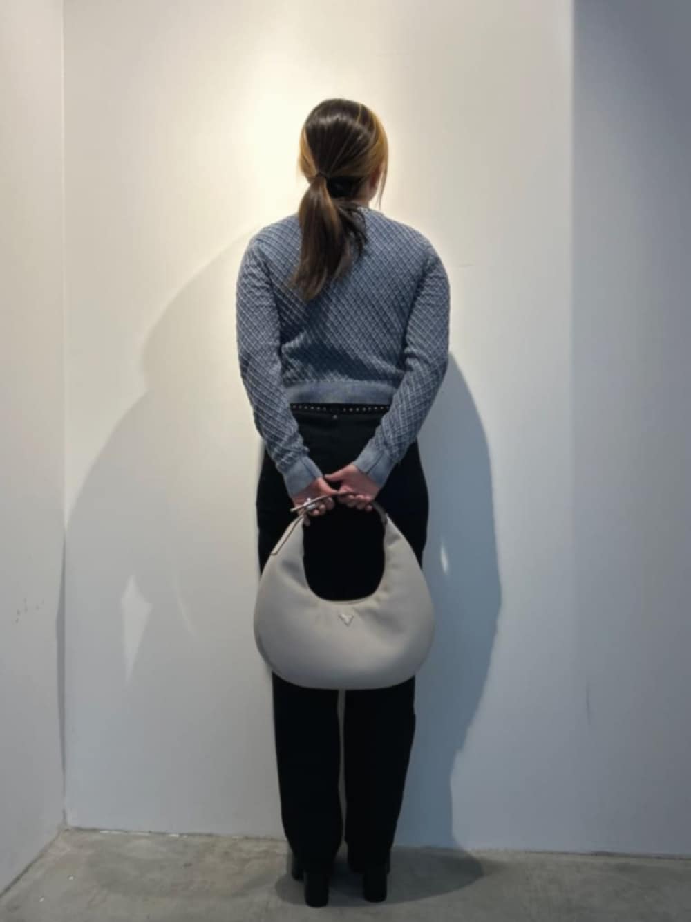 ブラック系のデニムパンツ、ベージュ系のハンドバッグ、グレー系のタンクトップを着用したレディースの冬コーディネートの2枚目の写真