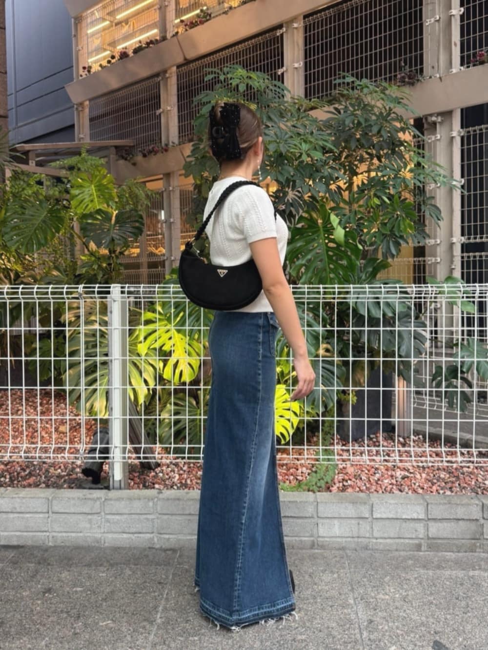 ブルー系のデニムスカート、ホワイト系のニット/セーター、ブラック系のショルダーバッグを着用したレディースの秋コーディネートの3枚目の写真