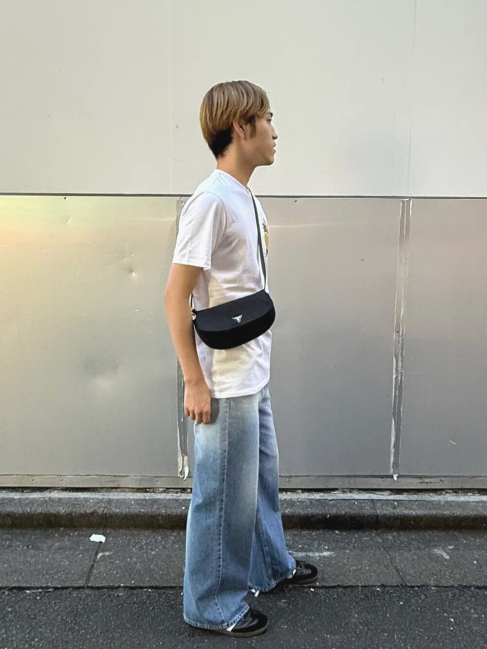 ホワイト系のTシャツ/カットソー、ブラック系のハンドバッグ、ブルー系のデニムパンツを着用したメンズの夏コーディネートの3枚目の写真