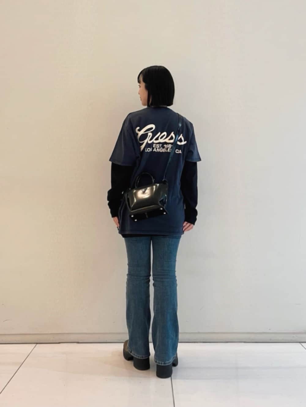 ブルー系のデニムパンツ、ブラック系のトートバッグ、ブラック系のTシャツ/カットソーを着用したレディースの冬コーディネートの2枚目の写真