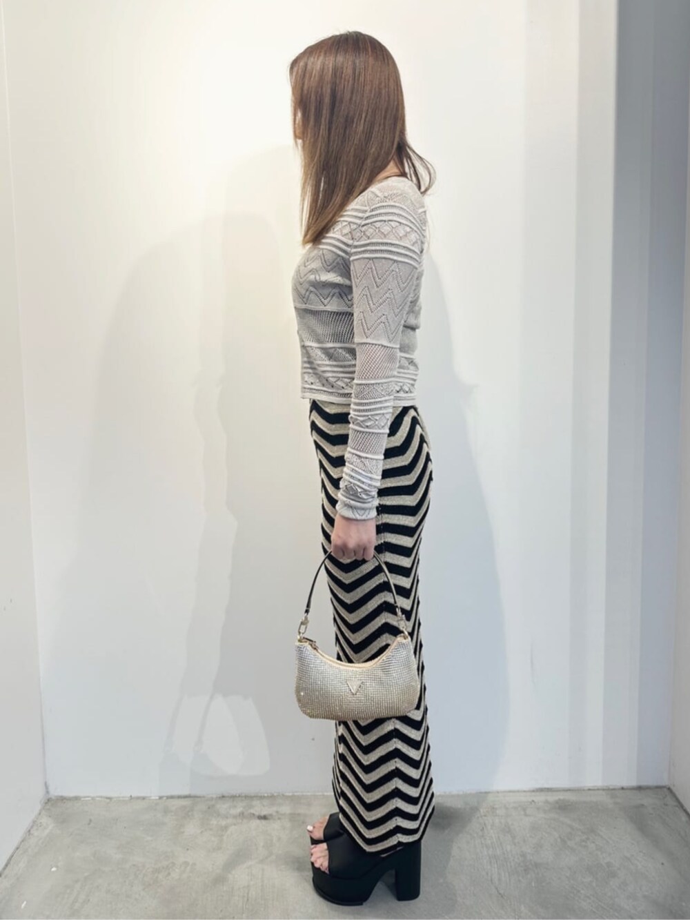 ゴールド系のハンドバッグ、ホワイト系のカーディガン/ボレロ、ブラック系のワンピースを着用したレディースの夏コーディネートの3枚目の写真