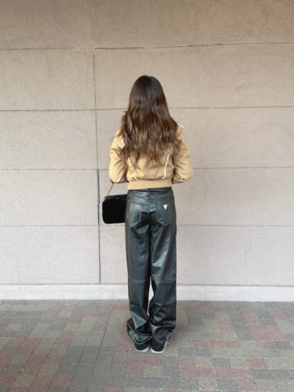 ブラック系のショルダーバッグ、ベージュ系のパーカー、ブラック系のその他パンツを着用したレディースの冬コーディネートの2枚目の写真