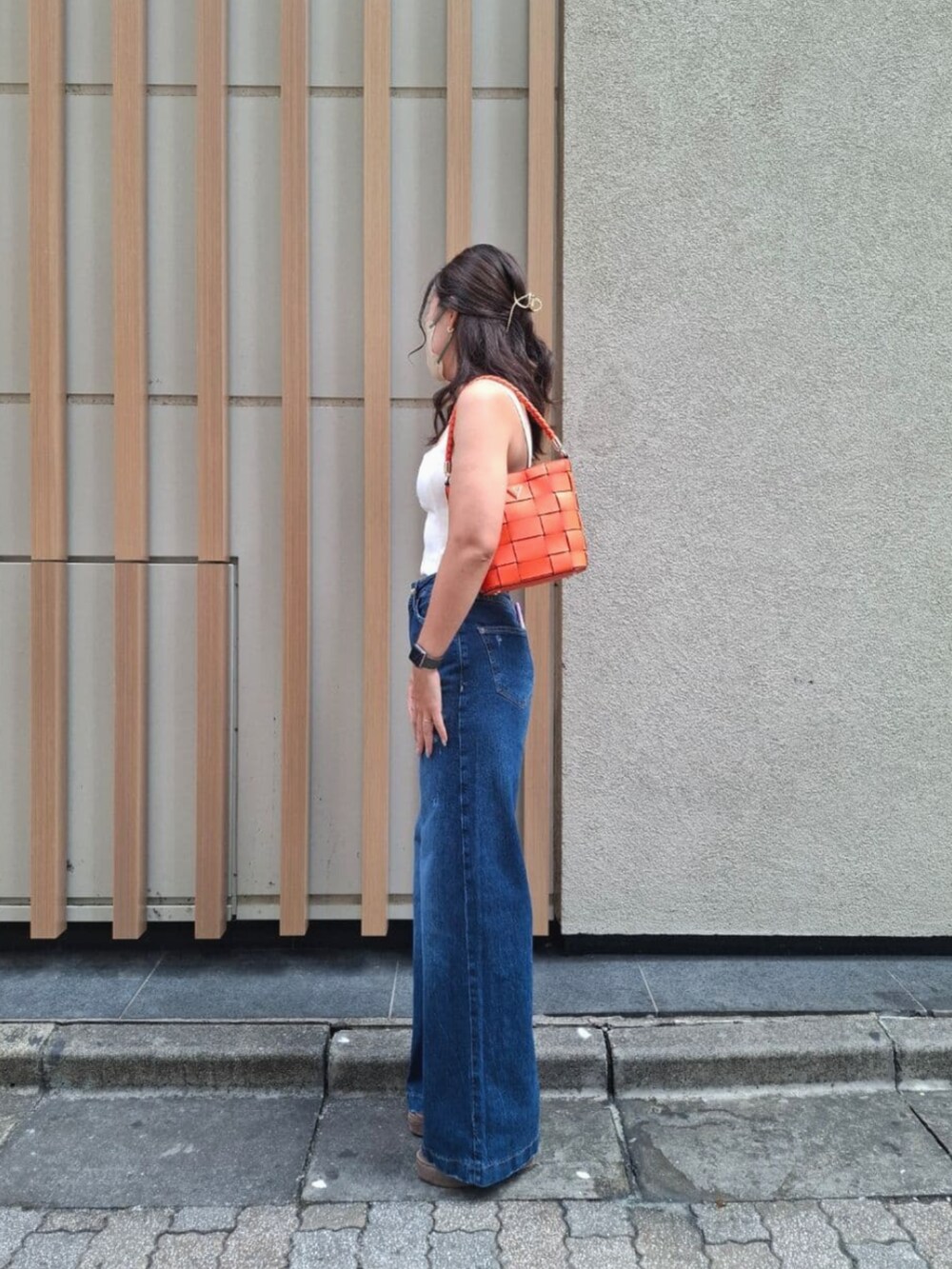 ブルー系のデニムパンツ、オレンジ系のショルダーバッグを着用したレディースの秋コーディネートの3枚目の写真