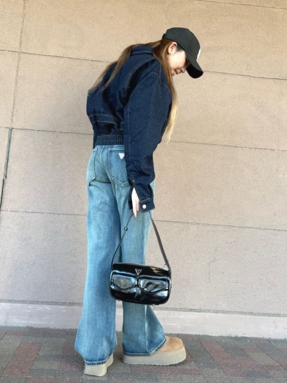 ブルー系のデニムジャケット、ブラック系のショルダーバッグ、ブルー系のデニムパンツを着用したレディースの春コーディネートの4枚目の写真