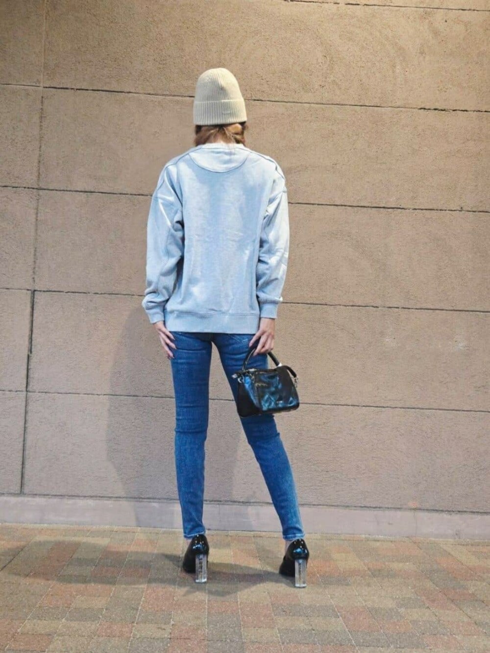 ブルー系のデニムパンツ、グレー系のスウェット、ブラック系のショルダーバッグを着用したレディースの秋コーディネートの2枚目の写真