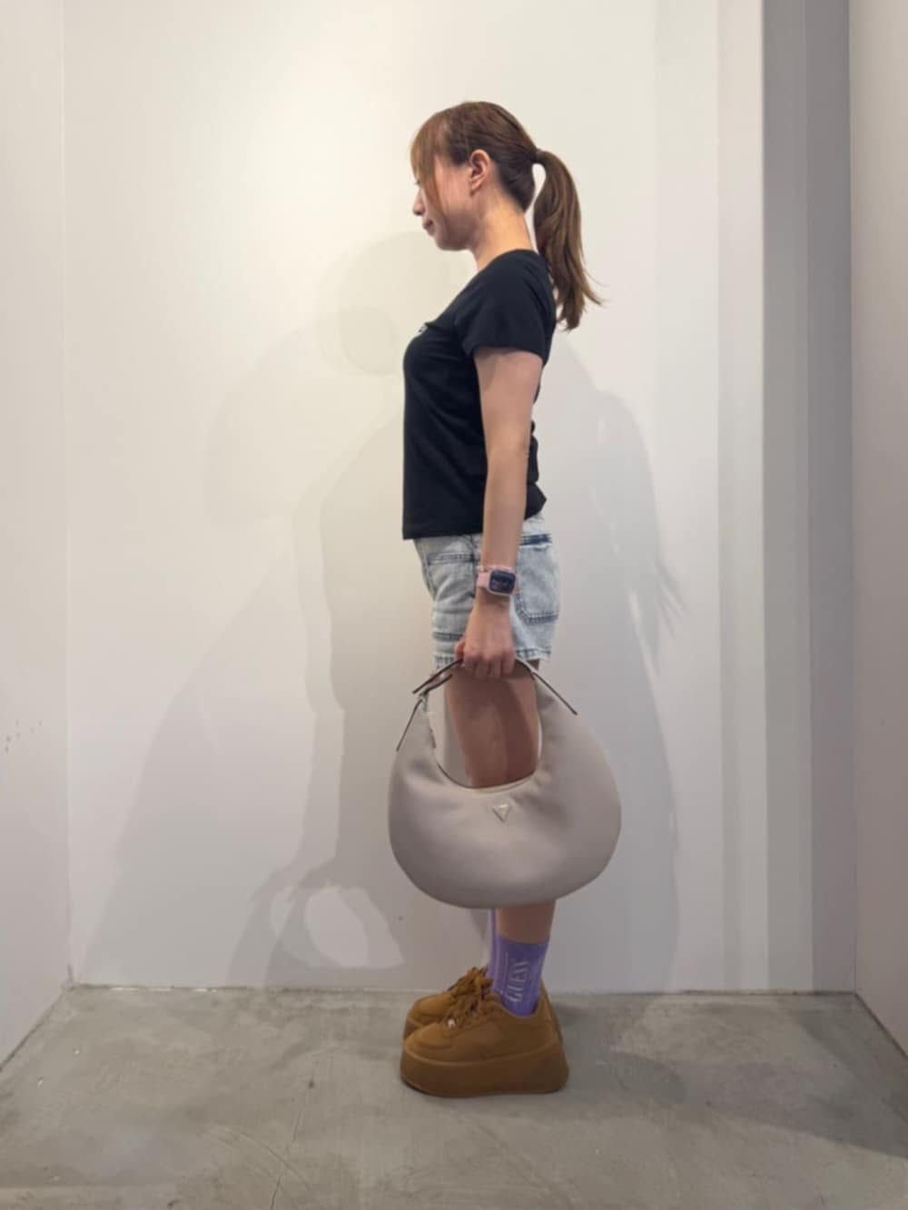 ブルー系のデニムパンツ、ベージュ系のハンドバッグ、ブラック系のTシャツ/カットソーを着用したレディースの冬コーディネートの3枚目の写真