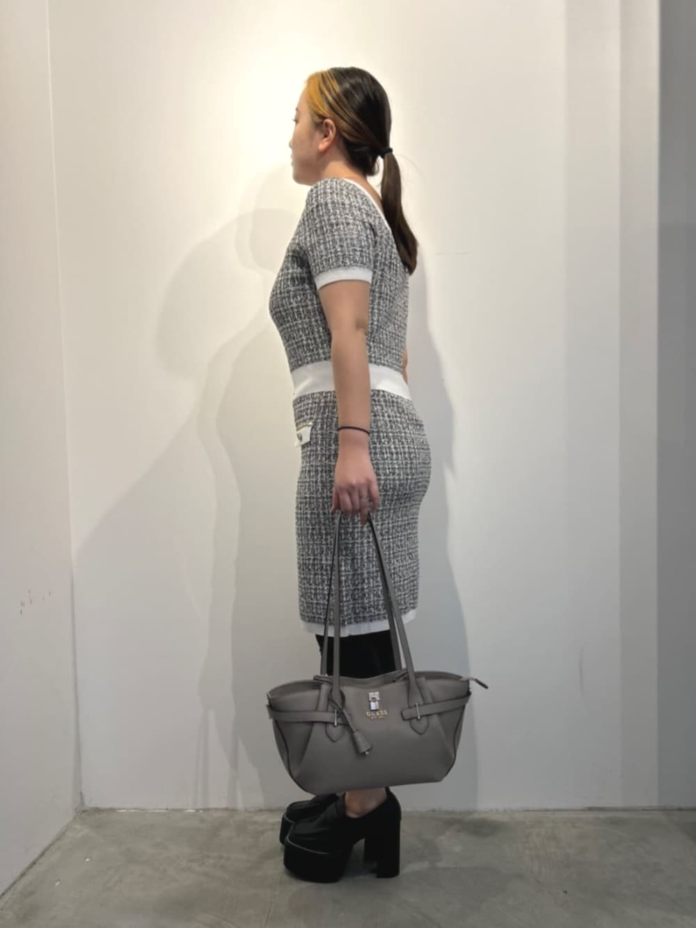 ベージュ系のトートバッグ、ブラック系のワンピースを着用したレディースの冬コーディネートの3枚目の写真