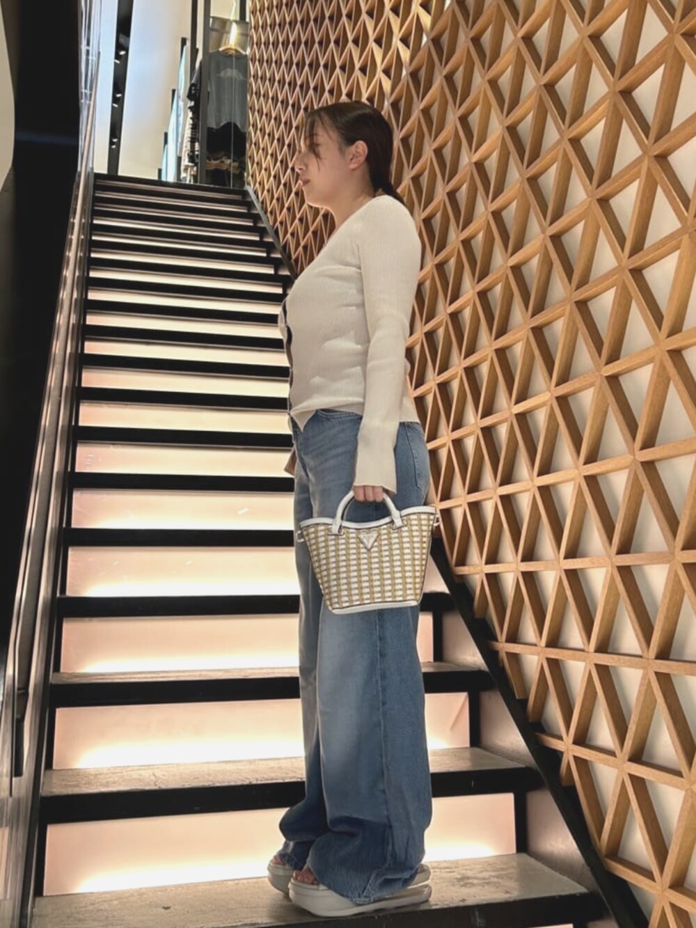 ホワイト系のショルダーバッグ、ブルー系のデニムパンツ、ホワイト系のニット/セーターを着用したレディースの夏コーディネートの3枚目の写真