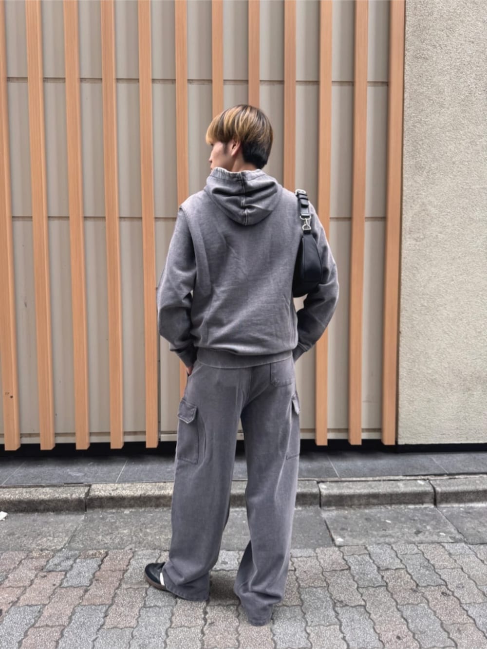 グレー系のパーカー、ブラック系のショルダーバッグを着用したメンズの秋コーディネートの2枚目の写真