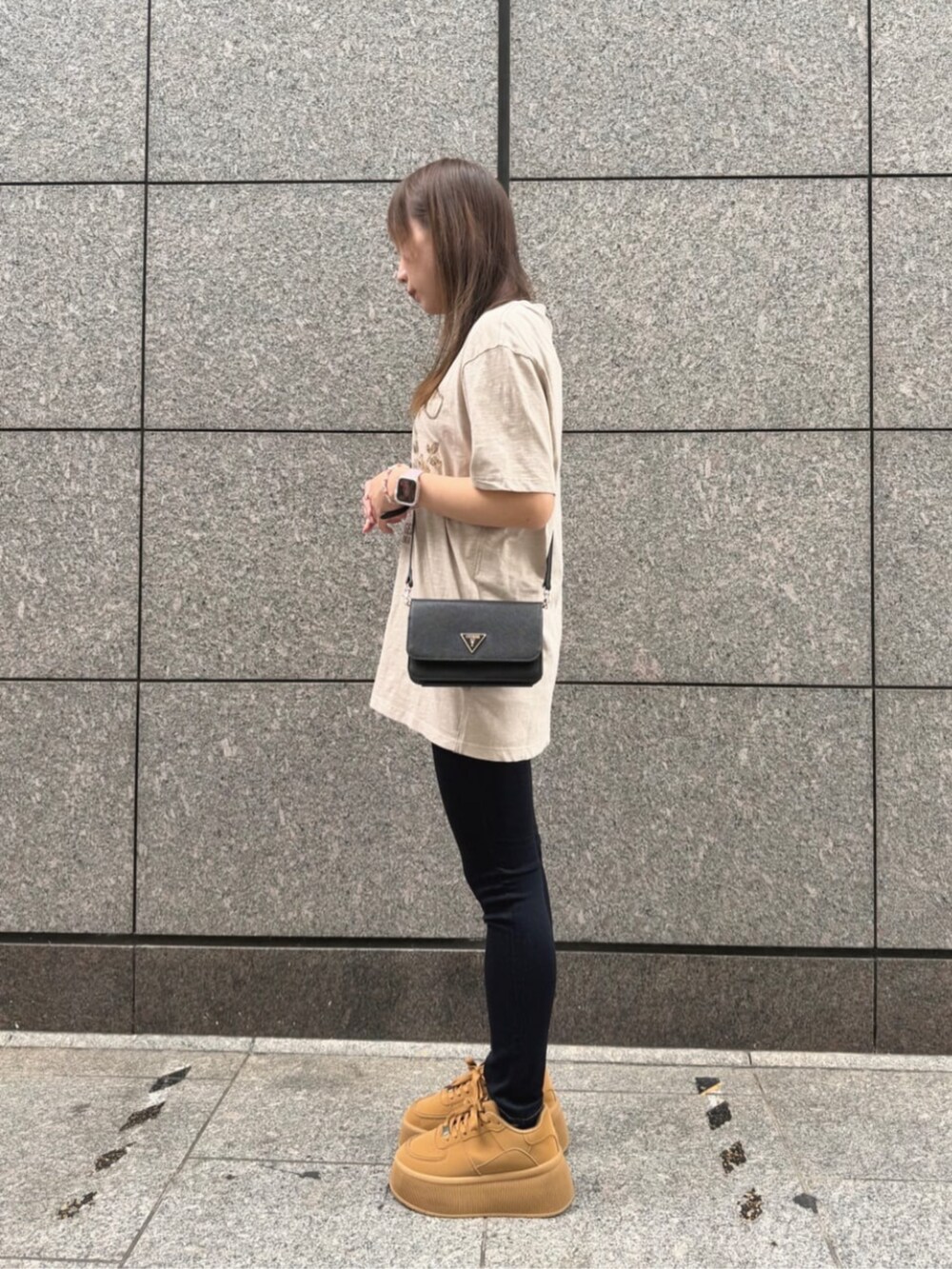 ブラック系のショルダーバッグ、ブルー系のデニムパンツ、ベージュ系のTシャツ/カットソーを着用したレディースの秋コーディネートの3枚目の写真