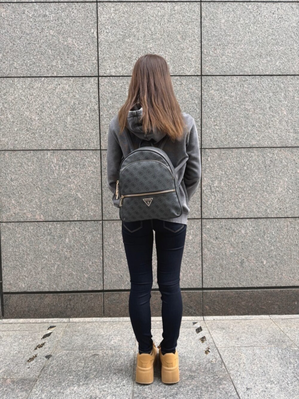 ブルー系のデニムパンツ、グレー系のバックパック/リュック、グレー系のパーカーを着用したレディースの秋コーディネートの2枚目の写真