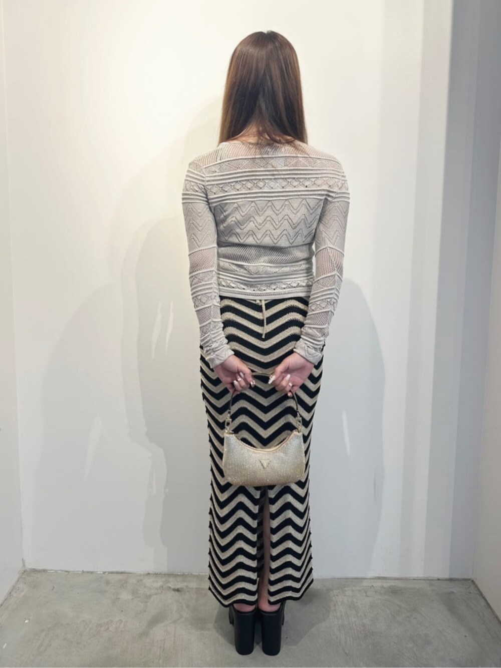 ゴールド系のハンドバッグ、ホワイト系のカーディガン/ボレロ、ブラック系のワンピースを着用したレディースの夏コーディネートの2枚目の写真