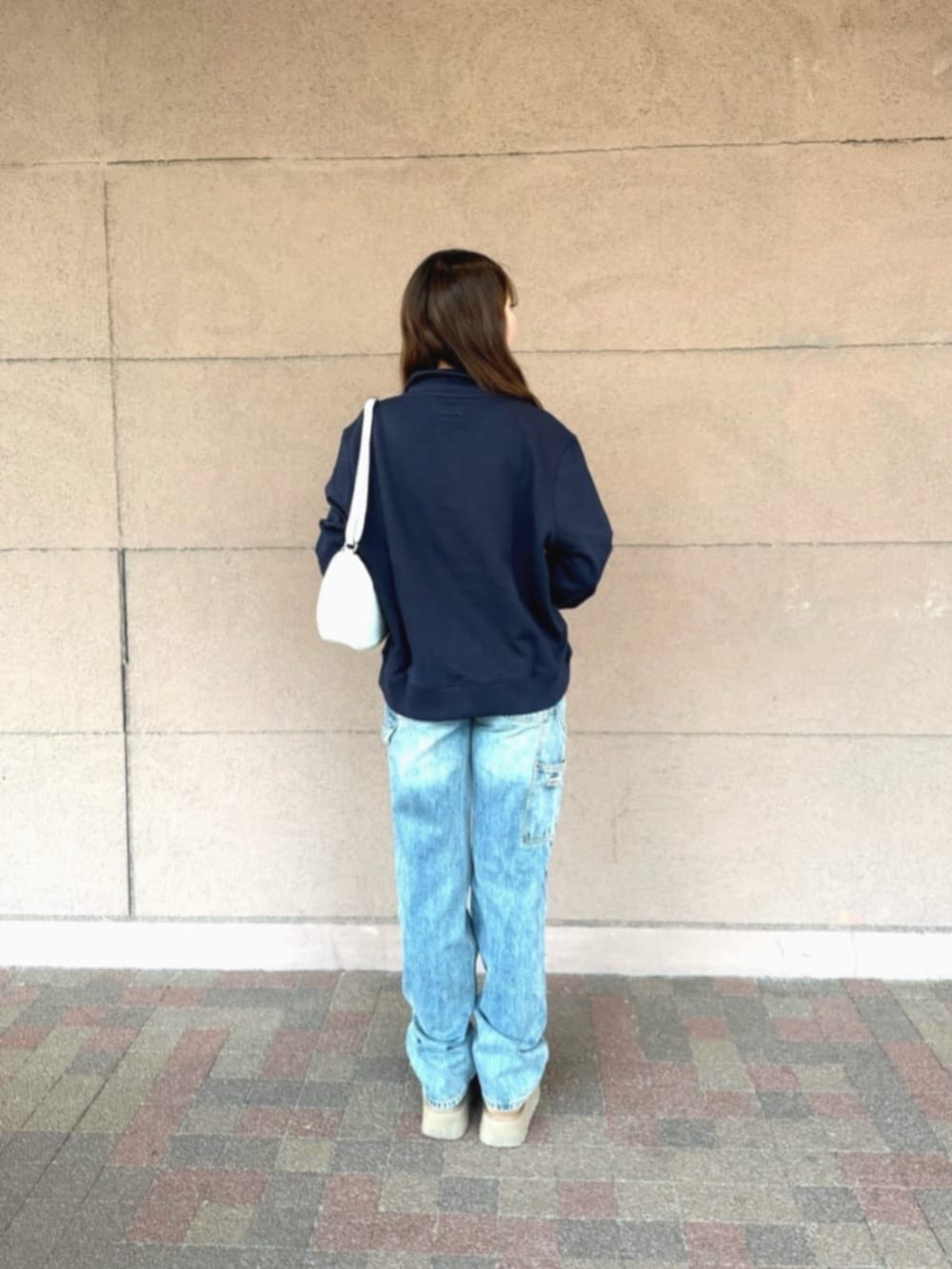 ブルー系のデニムパンツ、ホワイト系のハンドバッグ、ブルー系のスウェットを着用したレディースの冬コーディネートの2枚目の写真