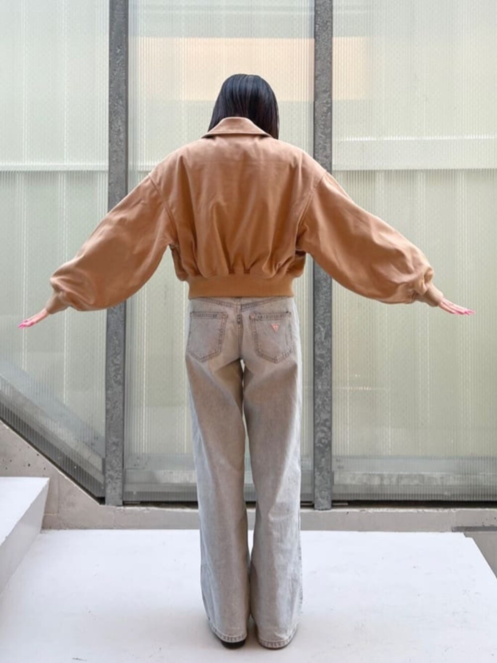 ブルー系のデニムパンツ、ベージュ系のブルゾンを着用したレディースの冬コーディネートの2枚目の写真