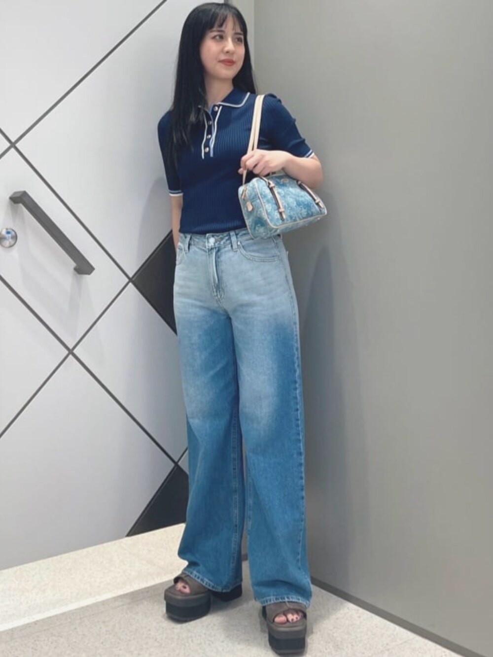 ブルー系のショルダーバッグ、ブルー系のポロシャツ、ブルー系のデニムパンツを着用したレディースの夏コーディネートの4枚目の写真