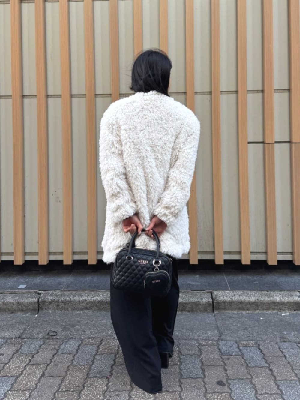 ブラック系のハンドバッグ、ブラック系のワンピース、ホワイト系のカーディガン/ボレロを着用したレディースの春コーディネートの4枚目の写真