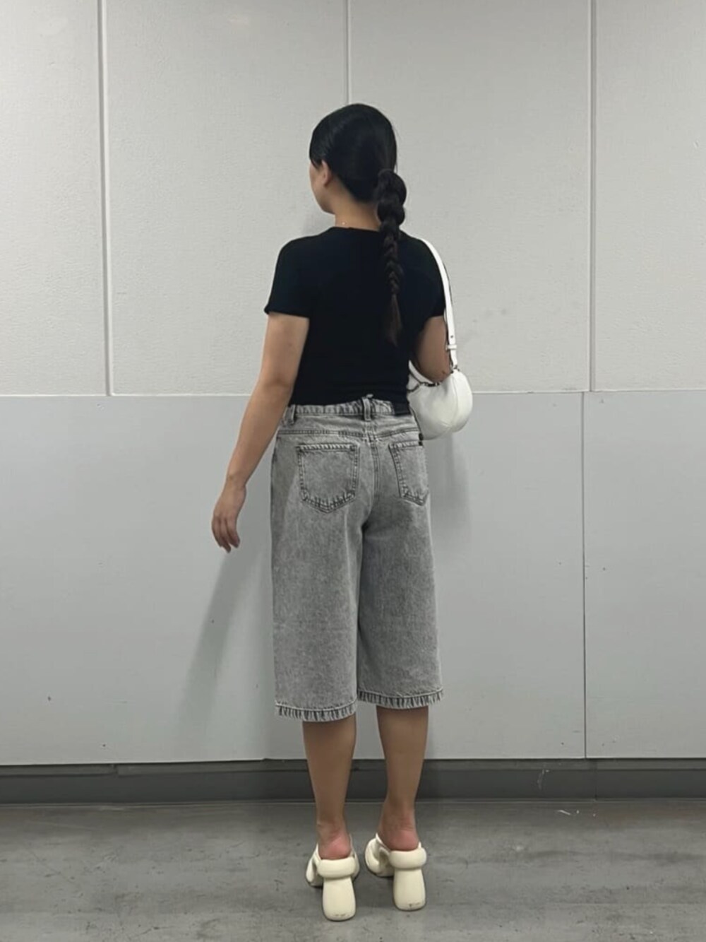 グレー系のデニムパンツ、ブラック系のTシャツ/カットソー、ホワイト系のハンドバッグを着用したレディースの夏コーディネートの2枚目の写真