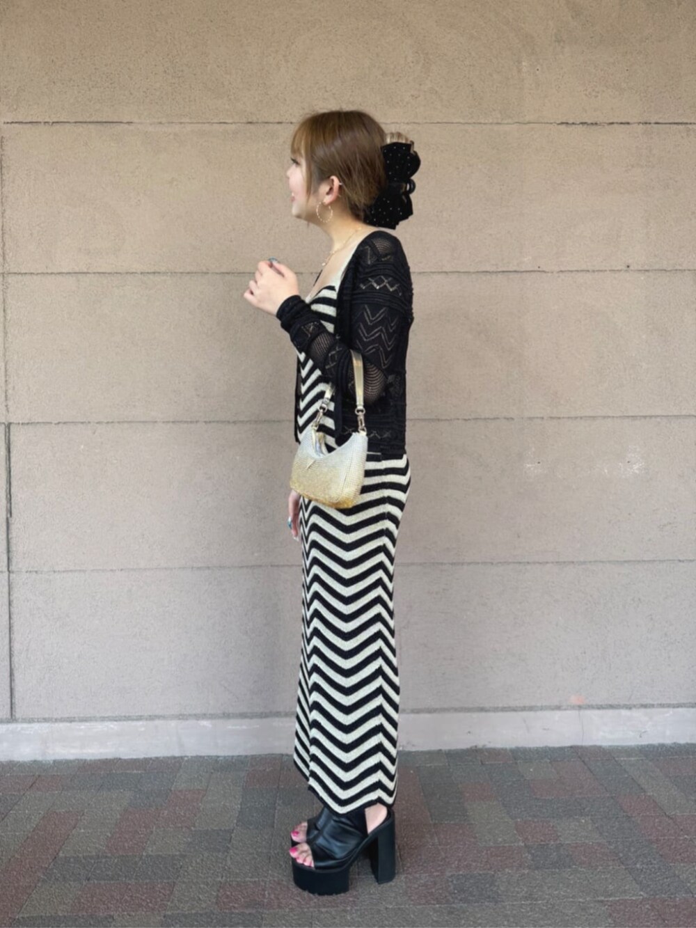 ゴールド系のハンドバッグ、ブラック系のワンピース、ブラック系のカーディガン/ボレロを着用したレディースの秋コーディネートの3枚目の写真