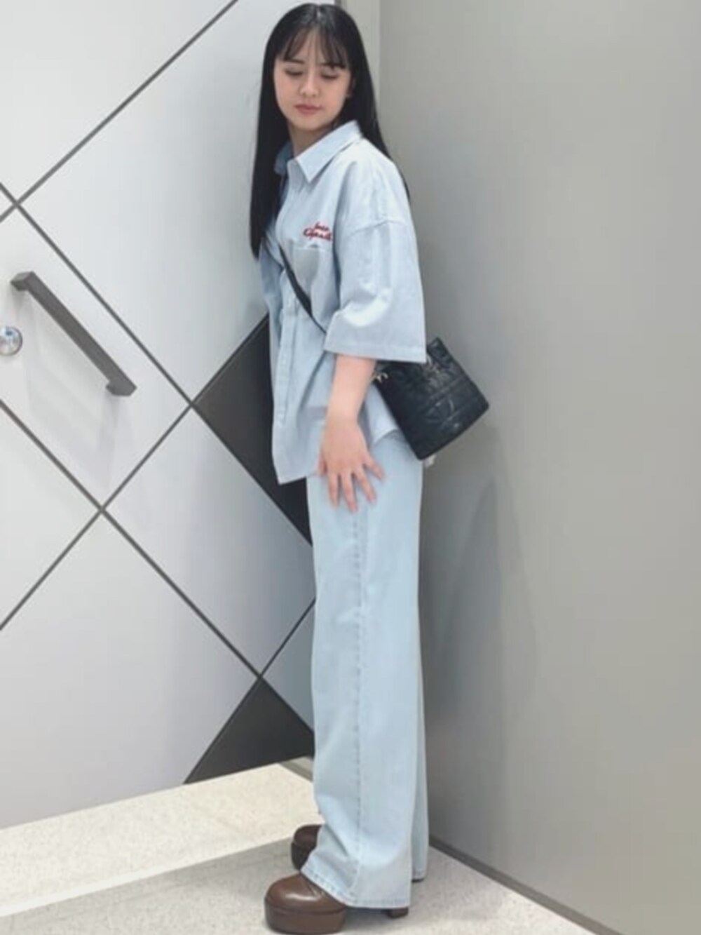 ブルー系のタンクトップ、ブルー系のデニムパンツ、ブラック系のショルダーバッグを着用したレディースの夏コーディネートの3枚目の写真