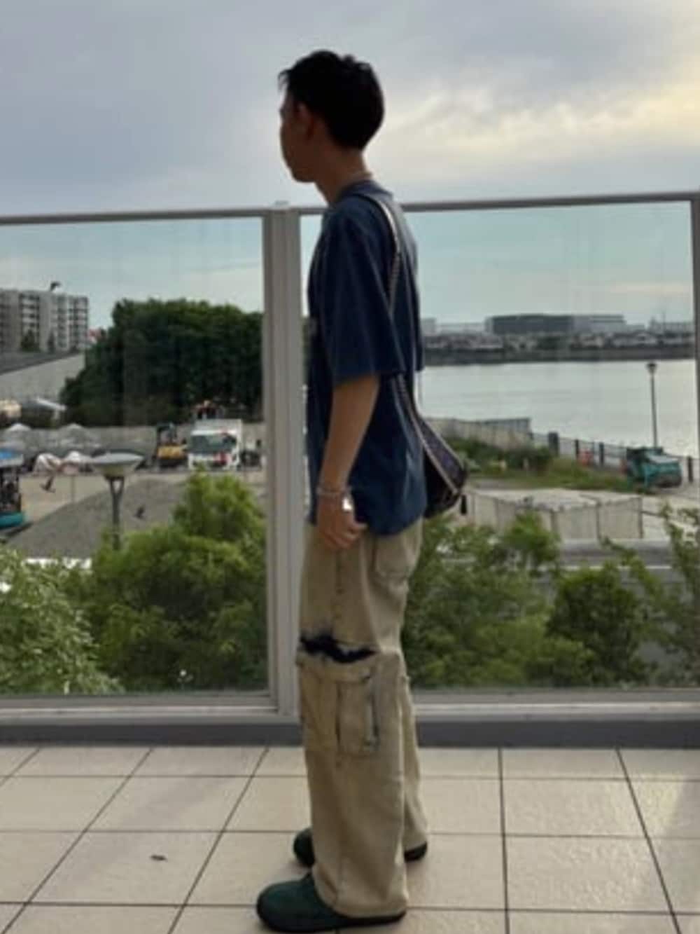 イエロー系のカーゴパンツ、ブルー系のショルダーバッグ、ブルー系のTシャツ/カットソーを着用したメンズの夏コーディネートの3枚目の写真