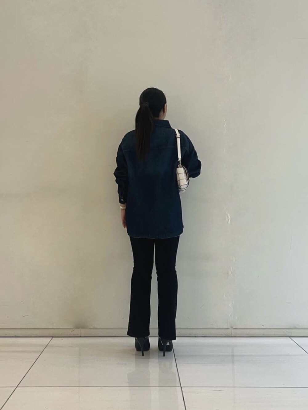 ブラック系のデニムパンツ、ブルー系のシャツ/ブラウス、ホワイト系のニット/セーターを着用したレディースの秋コーディネートの2枚目の写真