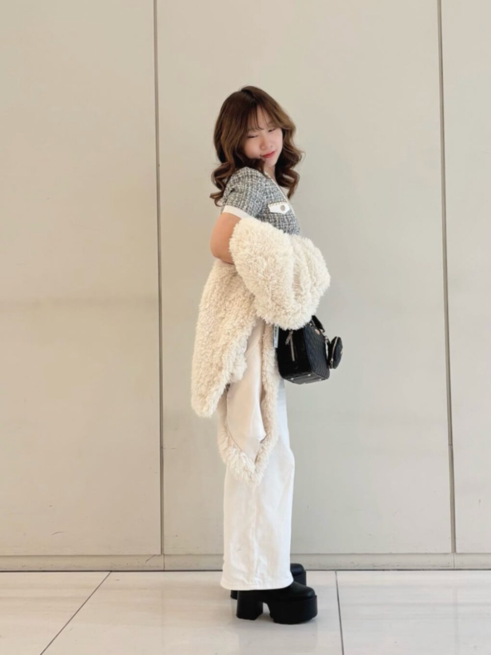 ホワイト系のデニムパンツ、ブラック系のハンドバッグ、ホワイト系のカーディガン/ボレロを着用したレディースの冬コーディネートの3枚目の写真