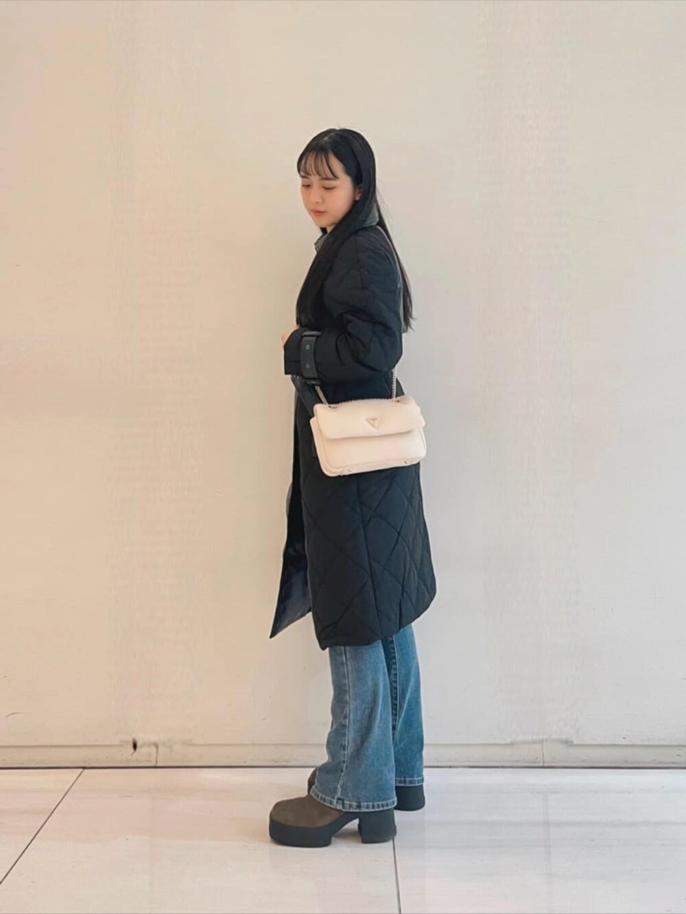 ブルー系のデニムパンツ、ホワイト系のニット/セーター、ホワイト系のショルダーバッグを着用したレディースの秋コーディネートの3枚目の写真