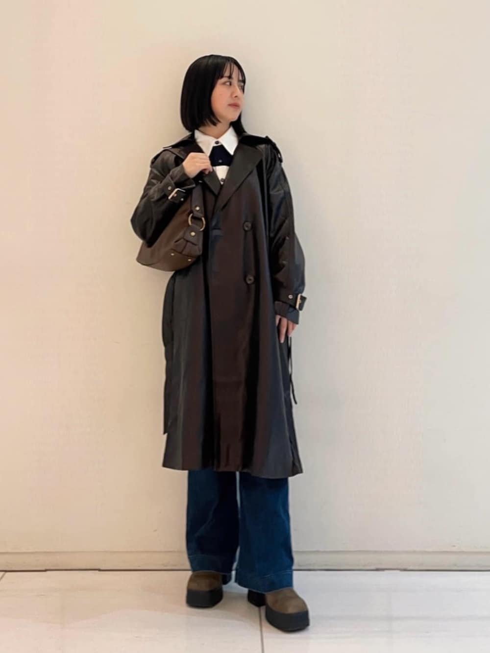 ブルー系のデニムパンツ、ブラウン系のショルダーバッグ、ブラウン系のトレンチコートを着用したレディースの春コーディネートの2枚目の写真