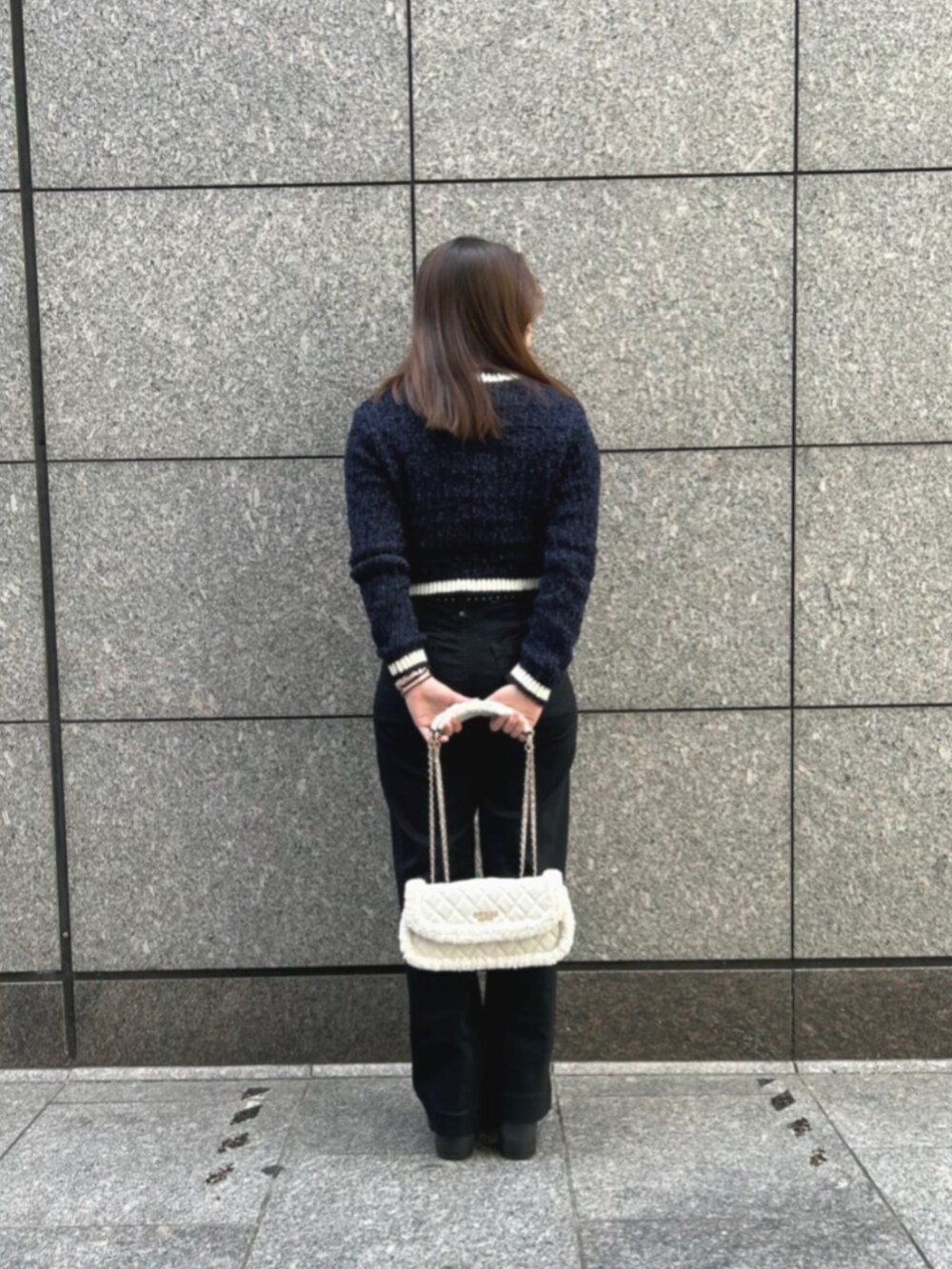 ブラック系のデニムパンツ、ブルー系のカーディガン/ボレロ、ホワイト系のショルダーバッグを着用したレディースの冬コーディネートの2枚目の写真