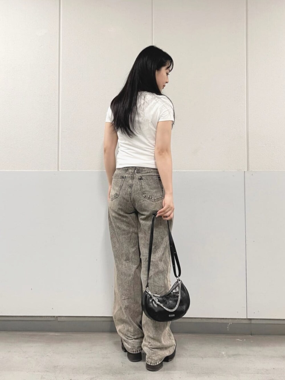 グレー系のデニムパンツ、ブラック系のハンドバッグ、ホワイト系のTシャツ/カットソーを着用したレディースの夏コーディネートの2枚目の写真