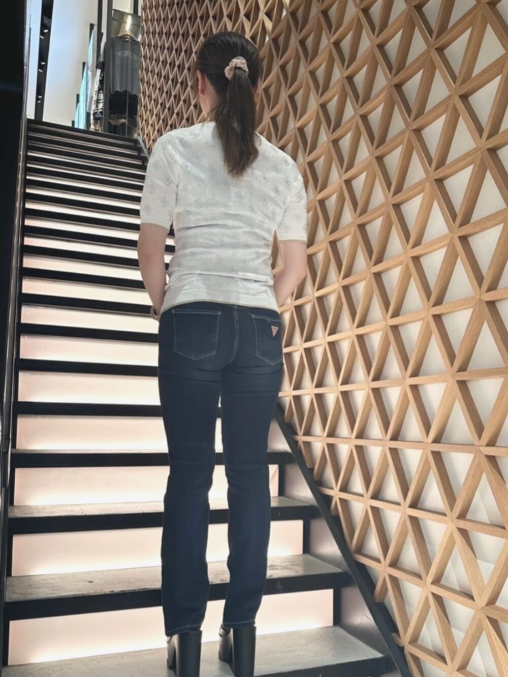 ホワイト系のショルダーバッグ、ベージュ系のニット/セーター、ブルー系のデニムパンツを着用したレディースの夏コーディネートの2枚目の写真