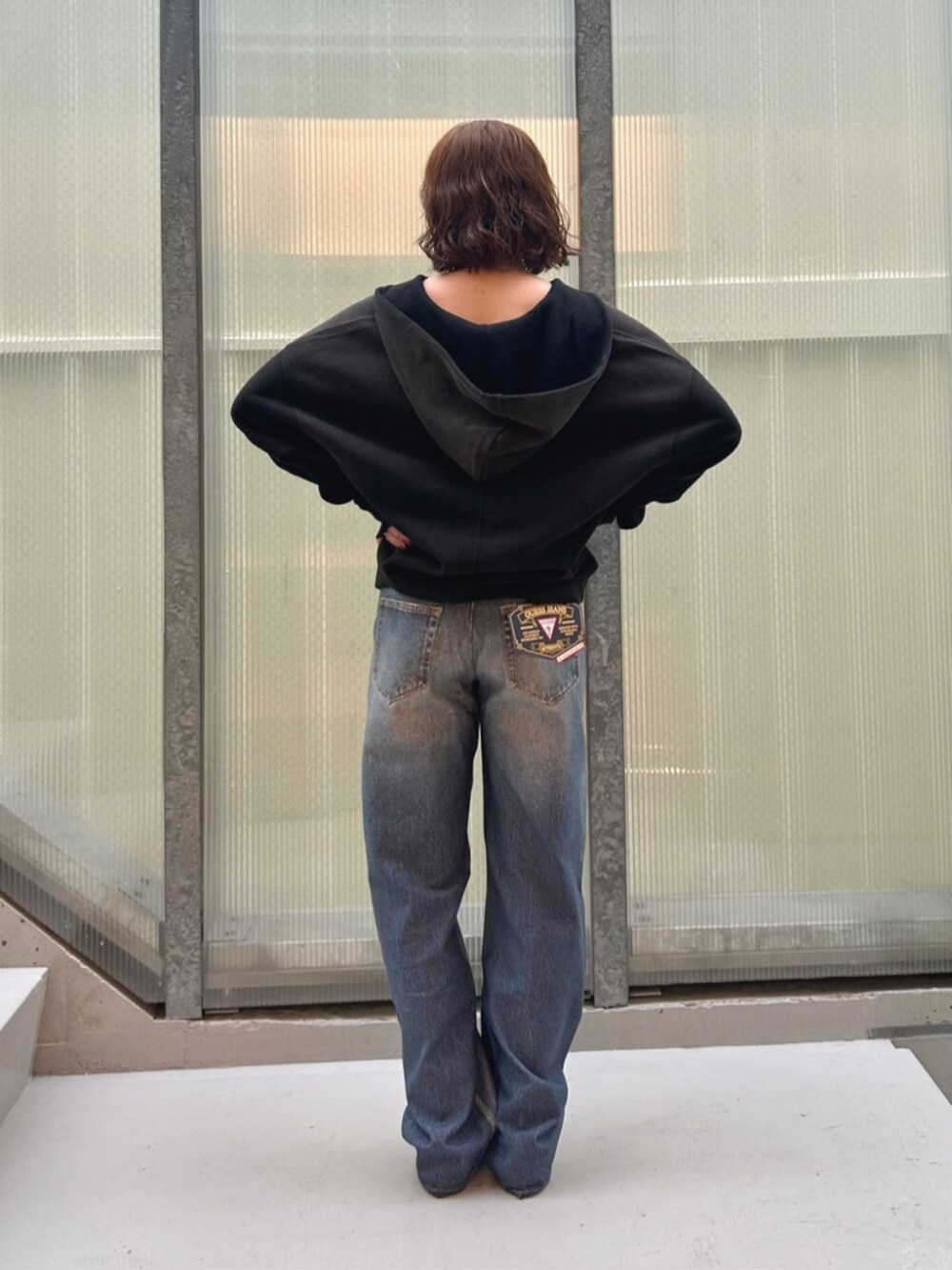 ブルー系のデニムパンツ、ブラック系のパーカーを着用したレディースの秋コーディネートの2枚目の写真