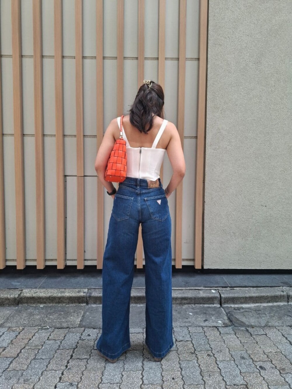 ブルー系のデニムパンツ、オレンジ系のショルダーバッグを着用したレディースの秋コーディネートの2枚目の写真