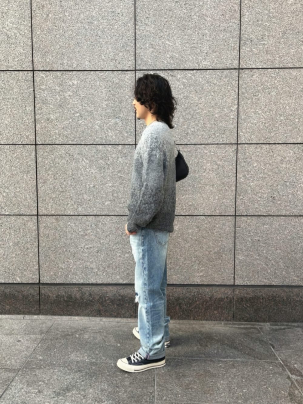 ブルー系のデニムパンツ、ブラック系のショルダーバッグ、グレー系のニット/セーターを着用したメンズの冬コーディネートの3枚目の写真