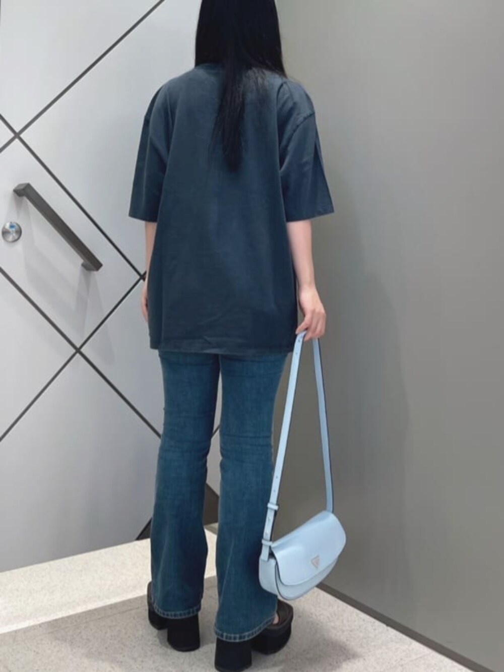 ブルー系のデニムパンツ、ブラック系のTシャツ/カットソー、ブルー系のハンドバッグを着用したレディースの夏コーディネートの2枚目の写真