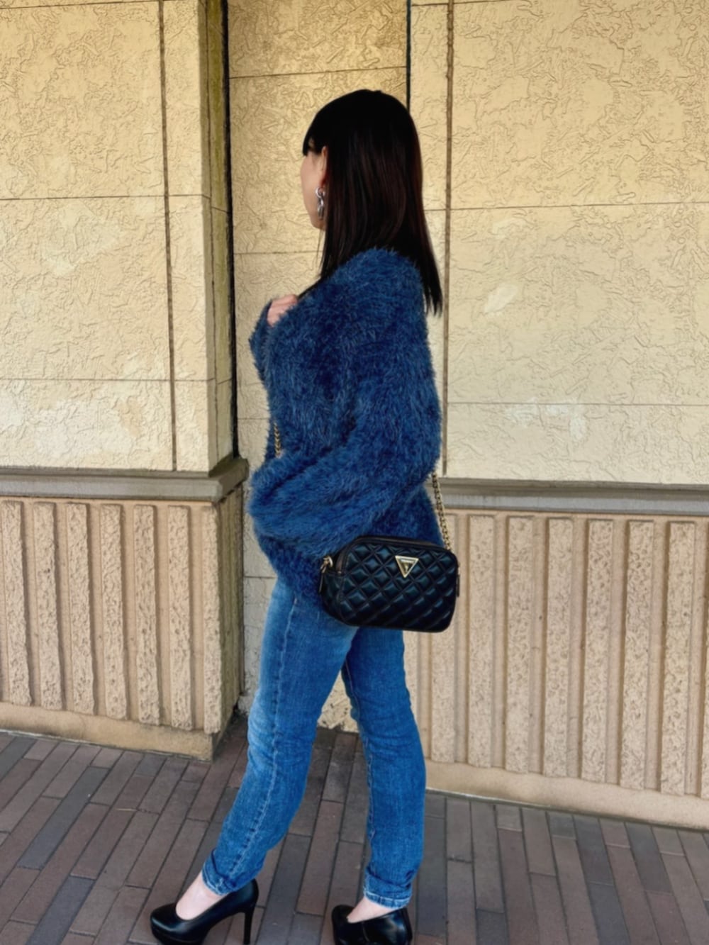 ブルー系のデニムパンツ、ブラック系のショルダーバッグ、ブルー系のニット/セーターを着用したレディースの冬コーディネートの3枚目の写真