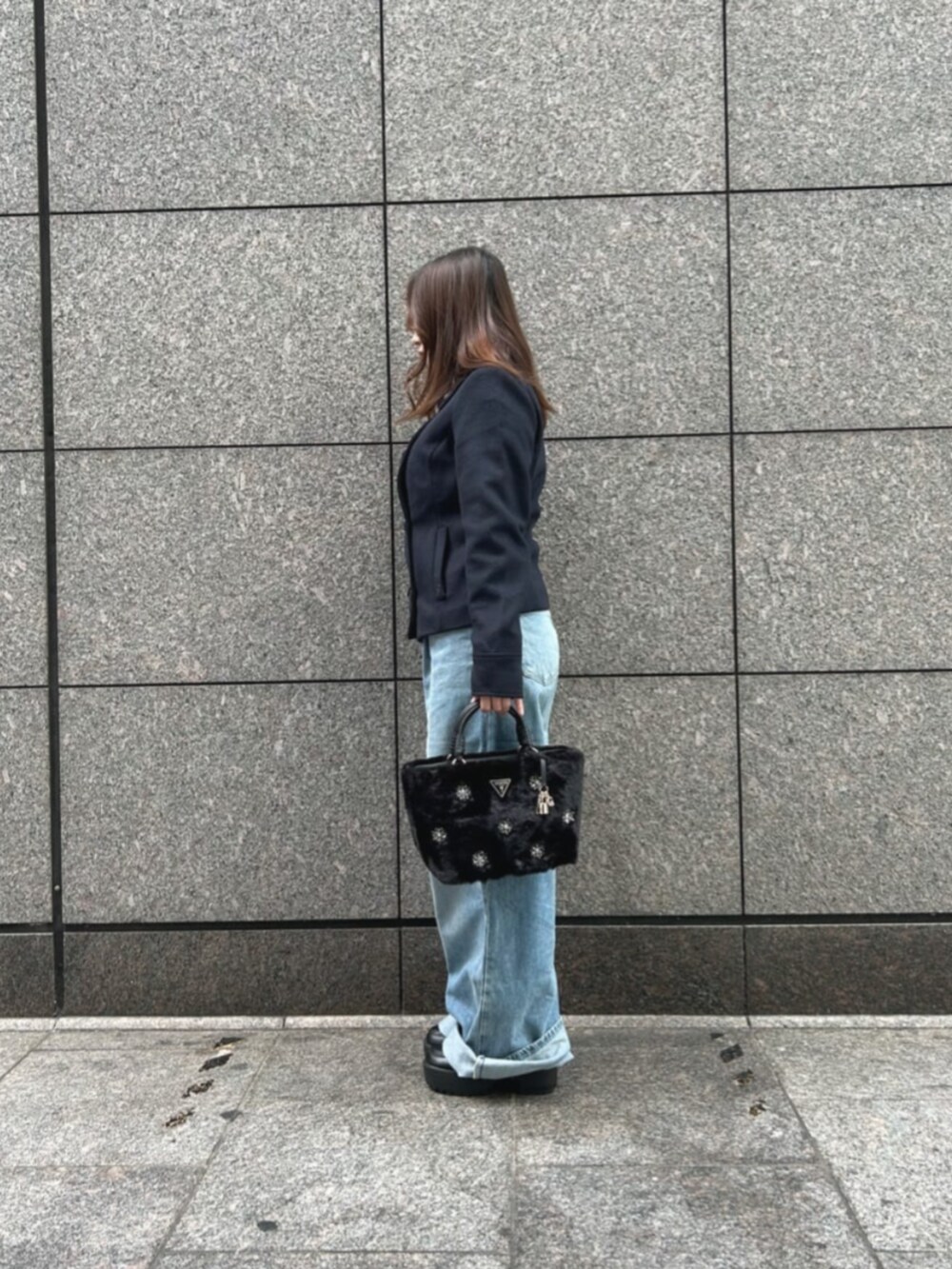 ブルー系のデニムパンツ、ブルー系のピーコート、ブラック系のショルダーバッグを着用したレディースの冬コーディネートの3枚目の写真